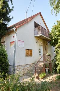 a white house with a staircase and a balcony at Tompos Vendégház és pince in Villány