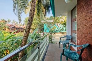 a balcony with two chairs and a palm tree at Celeste holiday homes in Calangute