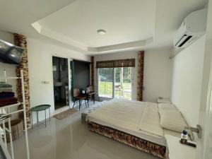 a bedroom with a bed and a desk and a window at Lee Red House Homestay in Ban Ao Yai