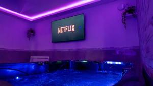 a bathroom with a tub with a television on the wall at MagicSpa91 in Chilly-Mazarin