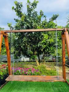 a wooden swing in a garden with flowers at เจเจรีสอร์ท in Ban Mo