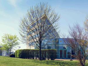un edificio con un albero di fronte di Mercure Poitiers Site du Futuroscope a Chasseneuil-du-Poitou