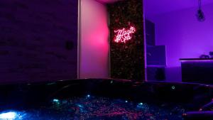 a room with a tub with a neon sign on a tree at MagicSpa91 in Chilly-Mazarin