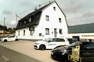 two cars parked in front of a white building at NürbLife Hotel in Nürburg