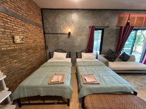 a room with two beds and a couch at Ban Buarawong บ้านบัวระวงค์ in Ban Nong Faek