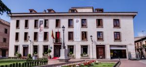 un grand bâtiment blanc avec des fleurs devant lui dans l'établissement Hotel El Bedel, à Alcalá de Henares