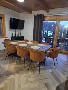 una sala da pranzo con tavolo, sedie e televisione di Stawowy Zakątek a Ruda Milicka