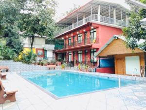 a building with a swimming pool in front of a building at Greenwood Resort in Dhamni