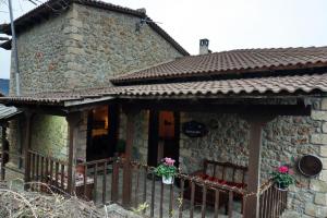 ein Steinhaus mit einem Zaun und Blumen darauf in der Unterkunft Ξενώνας Αστερωδή in Synikia Mesi Trikalon