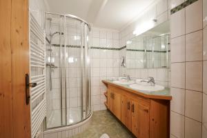 a bathroom with a shower and a sink and a mirror at Gourmet-Hotel Grünwald in Leogang