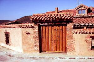 ein Backsteingebäude mit einer Holztür darauf in der Unterkunft Casa de Barro in Matarrubia