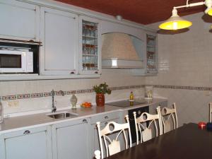 a kitchen with white cabinets and a table and chairs at Casa de Barro in Matarrubia