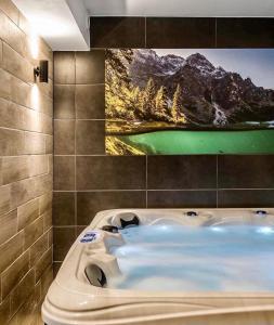 a bath tub in a bathroom with a painting on the wall at Villa Kaplowa Chata & SPA in Zakopane