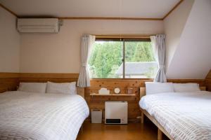 two beds in a room with a window at 日田天ヶ瀬の源泉掛け流し温泉付き貸別荘 5名様まで同料金 in Hita