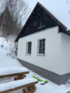 a house in the snow with two benches at Chaloupka in Karlova Studánka