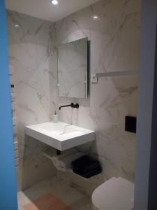 a white bathroom with a sink and a mirror at le dit vin secret in Aigues-Mortes