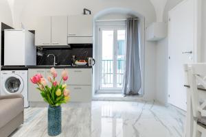 eine weiße Küche mit einer Vase mit Blumen darin in der Unterkunft APARTAMENT CHIARA - accanto alle scale dell amore - Julia Vieste in Vieste