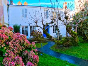 a garden with a tree and flowers in front of a house at Villa Simone - 200m de la Plage in Les Sables-d'Olonne