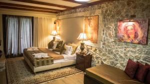 een slaapkamer met een kingsize bed in een stenen muur bij Archontopetra Boutique Hotel in Méga Khoríon +70 foto's