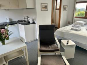 a room with a kitchen and a chair next to a bed at Studio Ittre in Ittre
