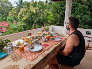 a man sitting at a table with food on it at Kiyara Holiday Villa in Ambalangoda