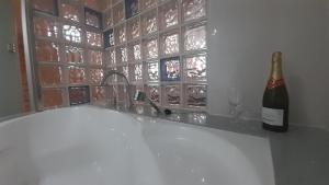 a bottle of wine sitting next to a bath tub at Ameli House By PECA in Silleda