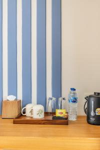 a wooden shelf with coffee cups and a bottle of water at Zana Villas in Krabi