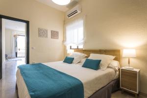 a bedroom with a large bed with blue pillows at Hommyhome San Isidoro in Seville