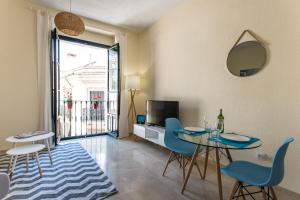 a living room with a table and chairs and a television at Hommyhome San Isidoro in Seville