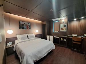 een slaapkamer met een groot wit bed en een bureau bij 그랑메종바오밥호텔 in Samgong-ni