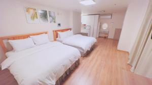 two beds in a hotel room with white sheets at Whouse-sinchon in Seoul