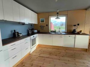 a large kitchen with white cabinets and a window at Lofoten Seaside House in Offersøya
