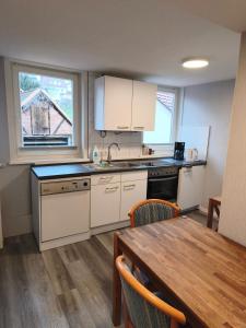 una cucina con mobili bianchi e un tavolo di legno di Gasthaus Jütte a Ebergötzen