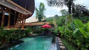 a pool in a garden with a red umbrella at Wana Bamboo House by ecobreeze in Sidemen