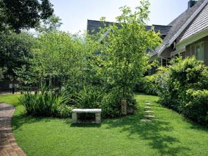 un giardino con panchina di fronte a un edificio di Wild Tree Lodge a Benoni