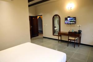 een slaapkamer met een bed, een bureau en een televisie bij THE SUNSET BAY in Fort Kochi
