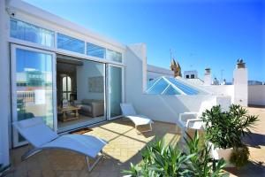 een patio met 2 stoelen en een bank op een balkon bij El Armador Casa Palacio by Luxury Suites Cádiz in Cádiz