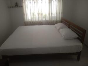 a bedroom with a bed with white sheets and a window at Jayasri in Hikkaduwa +17 photos