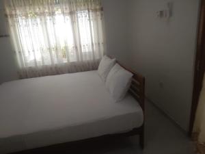a bedroom with a bed with white sheets and a window at Jayasri in Hikkaduwa