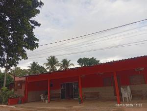 een rood gebouw met witte stoelen ervoor bij Pousada Jalapão Rosa do deserto in Mateiros