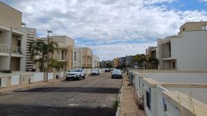 een straat met auto's die door een straat met gebouwen rijden bij Casa PERLAMARE in Otranto