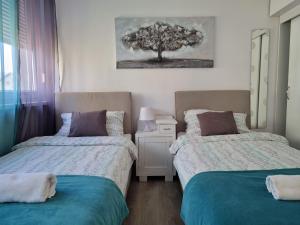 a bedroom with two beds and a tree on the wall at Apartman Lipik in Lipik