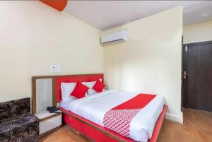 a bedroom with a red and white bed and a chair at Hotel Vanice Blue in Indore