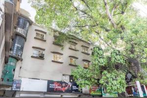 a building with windows and a tree in front of it at Hotel Vanice Blue in Indore