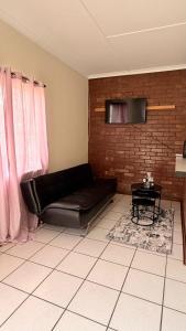 a living room with a black leather couch and a table at Gaxela Space in Pietermaritzburg
