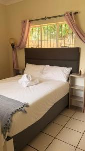 a bedroom with a large bed with a window at Gaxela Space in Pietermaritzburg +5 photos