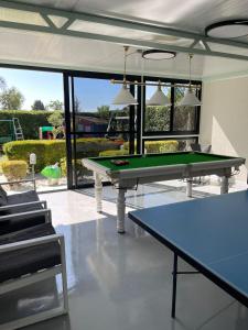 un tavolo da ping pong in una stanza con finestre di מור ולבונה - וילה מהממת ומפנקת למשפחות בגליל a Sifsufa Altre 31 foto