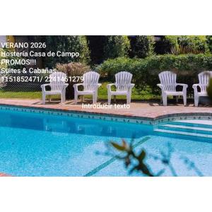 un gruppo di sedie bianche accanto alla piscina di Hostería Casa de Campo a Chascomús