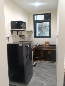 a kitchen with a black refrigerator in a room at Diamond Ridge Living 1RK G-02 in Haidar Sāhibgūda