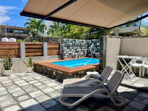 a swimming pool with chairs and a table and an umbrella at Turquoise Bay Beach Apartments Trou d'Eau Douce in Trou d'Eau Douce